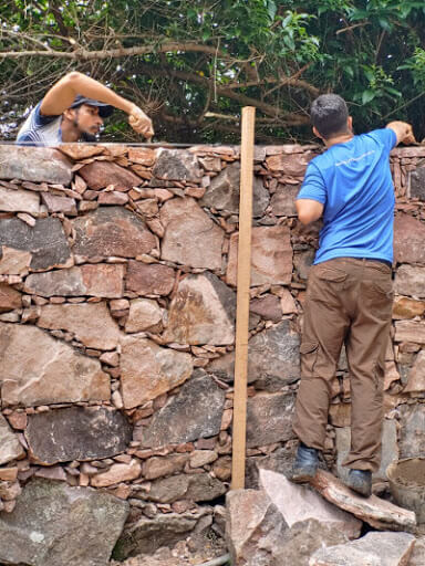 pessoas construindo um muro de pedras